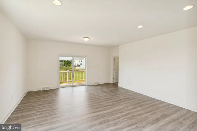 a view of an empty room with wooden floor and windows