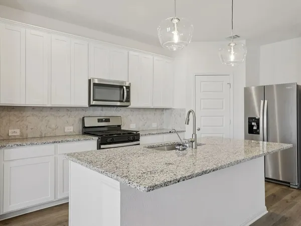 a kitchen with granite countertop a sink a center island and cabinets