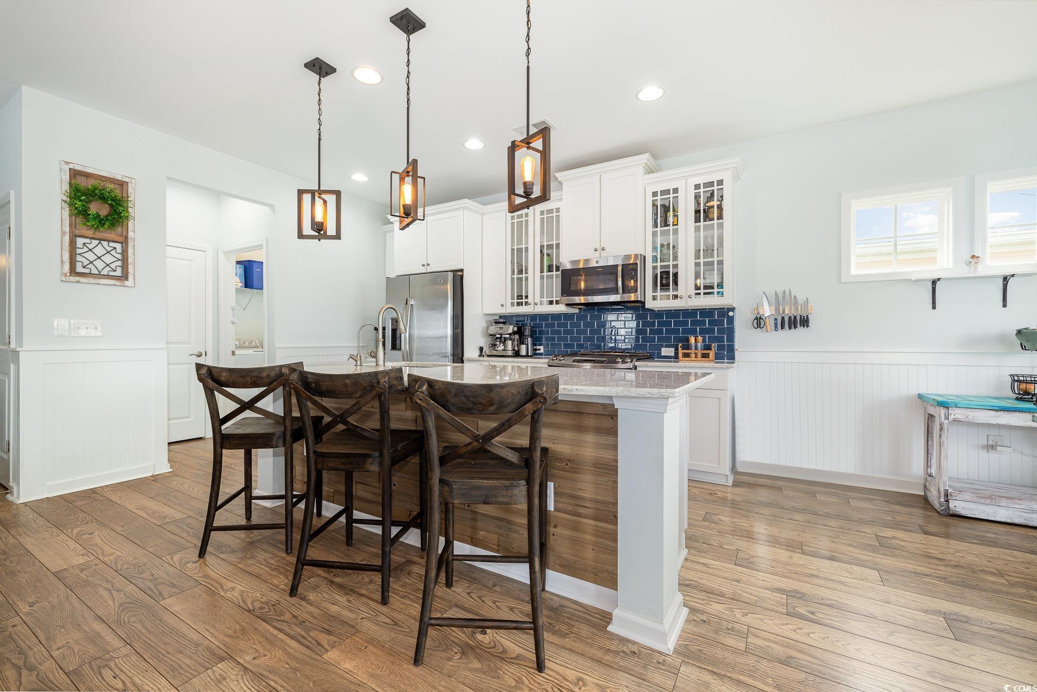 136 Splendor Circle Murrells Inlet, SC 29576 - Photo 6 of 30 Kitchen with wainscoting, light wood-style flooring, a kitchen bar, and stainless steel appliances