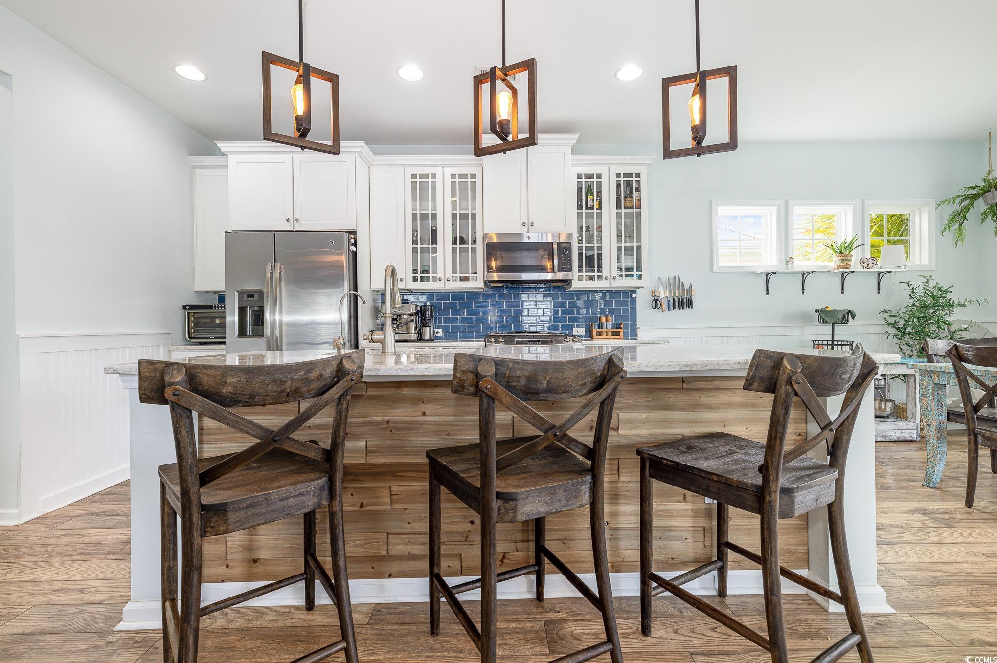 136 Splendor Circle Murrells Inlet, SC 29576 - Photo 7 of 30 Kitchen with light wood-type flooring, a kitchen bar, appliances with stainless steel finishes, and wainscoting