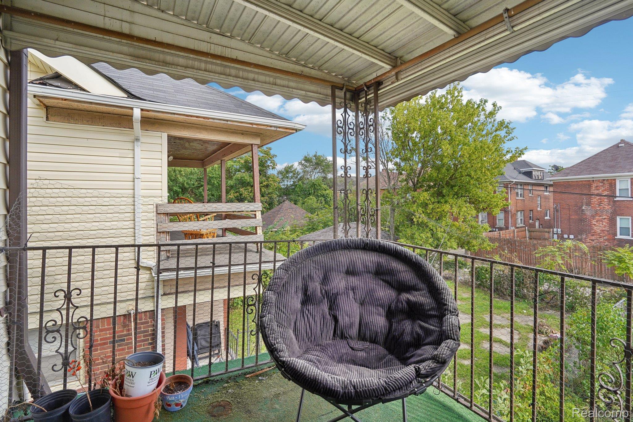 4101 Pasadena Street Detroit, MI 48238 - Photo 33 of 42 Covered outdoor balcony with ornate metal railings, featuring a textured ceiling and a covered porch on an adjacent structure