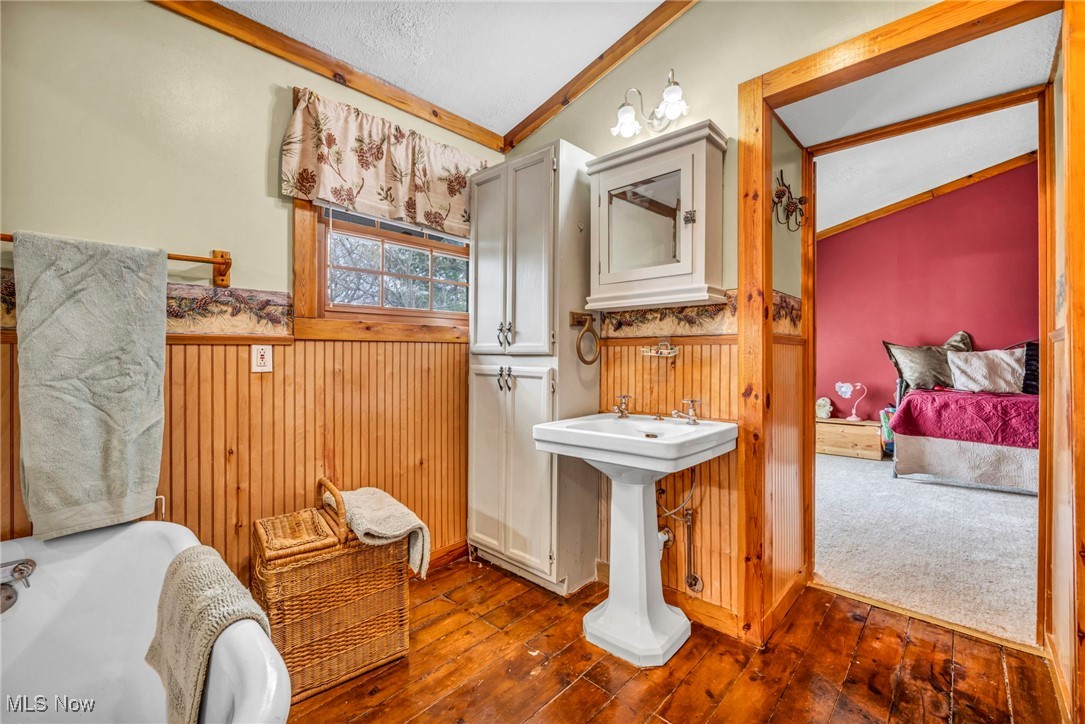 24455 Tryon Road Oakwood, OH 44146 - Photo 37 of 40 Bathroom with wainscoting, vaulted ceiling, an inviting chandelier, crown molding, and wood-type flooring