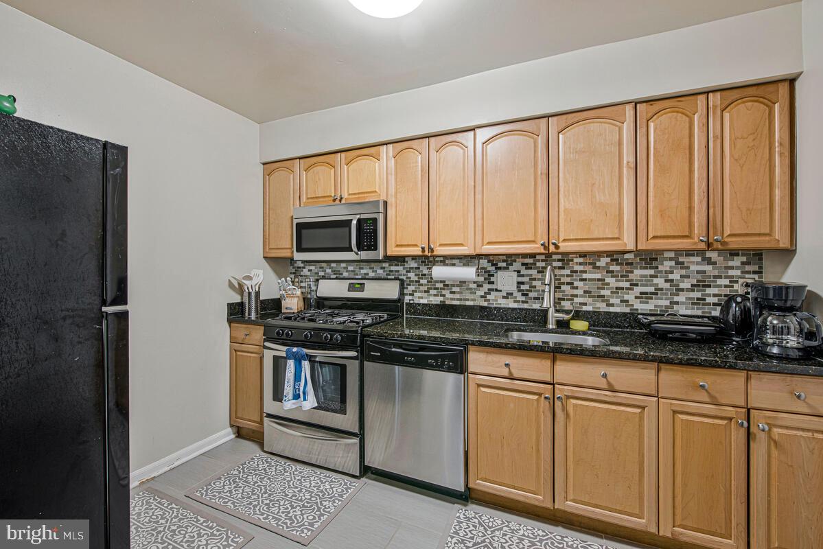 9695 Hitching Post Lane, Unit H Laurel, MD 20723 - Photo 6 of 19 a kitchen with stainless steel appliances granite countertop a stove a sink and a refrigerator
