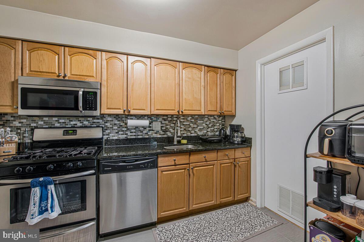 9695 Hitching Post Lane, Unit H Laurel, MD 20723 - Photo 7 of 19 a kitchen with stainless steel appliances granite countertop a stove microwave and cabinets