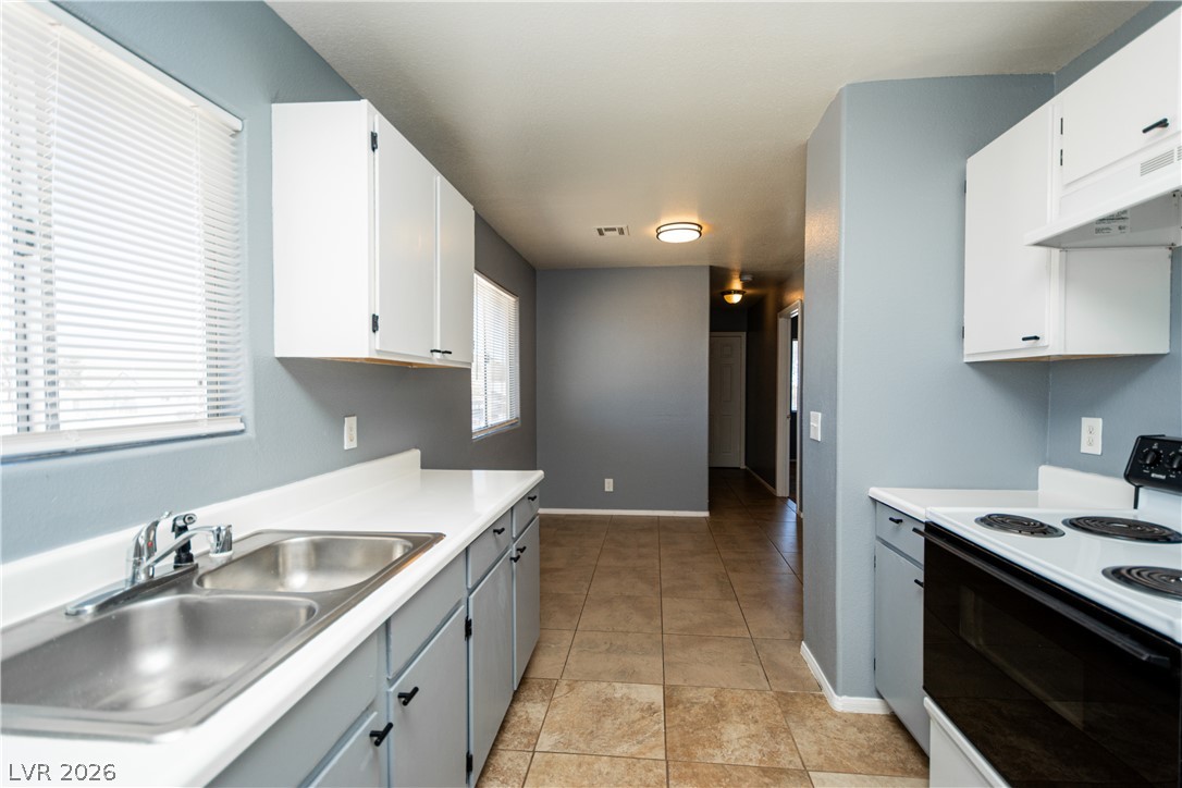 1444 Star Road Pahrump, NV 89048 - Photo 9 of 37 Crisp white cabinetry paired with durable tile flooring defines this functional kitchen space.