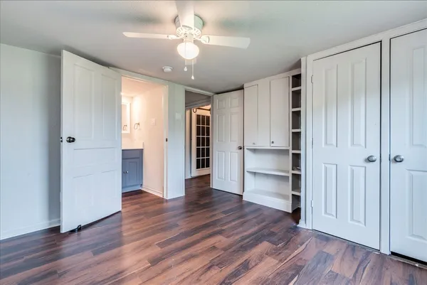 an empty room with wooden floor closet and windows