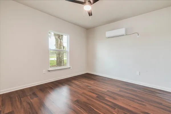 an empty room with wooden floor and windows