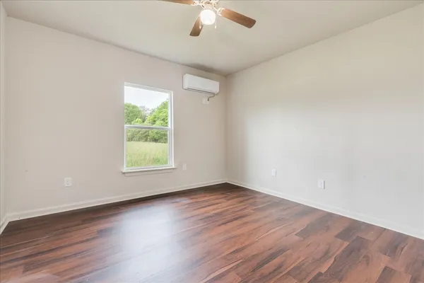 an empty room with wooden floor chandelier fan and window