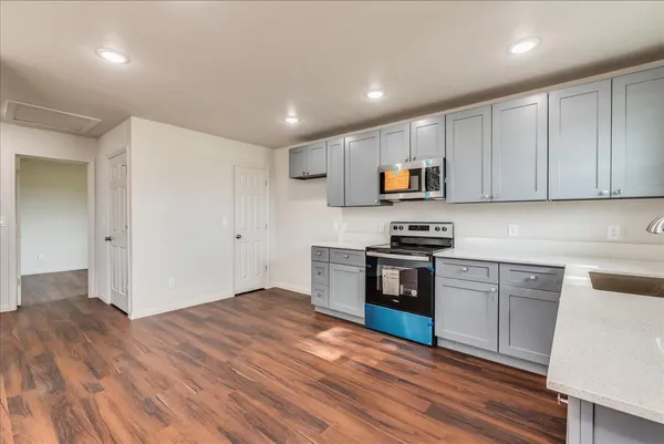 a kitchen with granite countertop a stove and a wooden floor