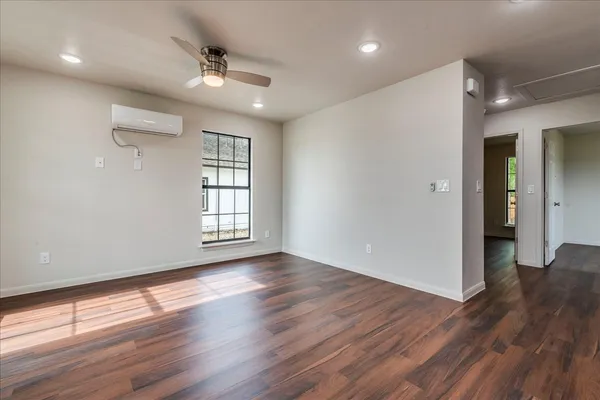 a view of an empty room with wooden floor and a window