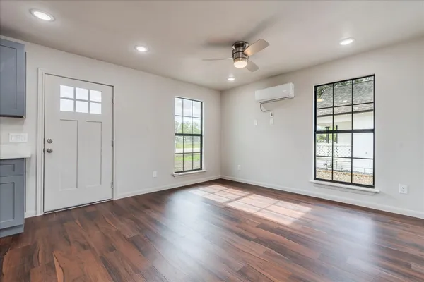 a view of an empty room with wooden floor and window
