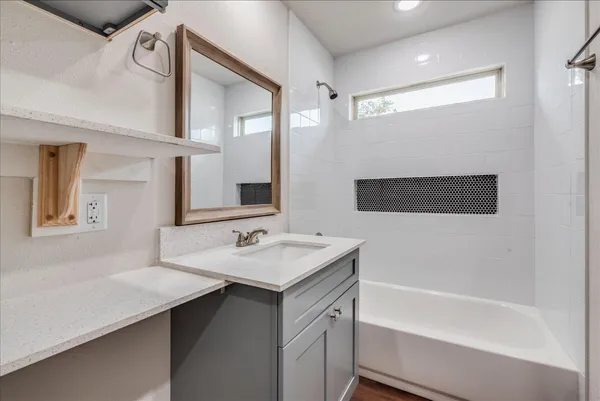 a bathroom with a sink a bathtub a mirror a vanity and a shower