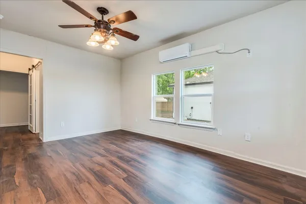 a view of an empty room with window and wooden floor