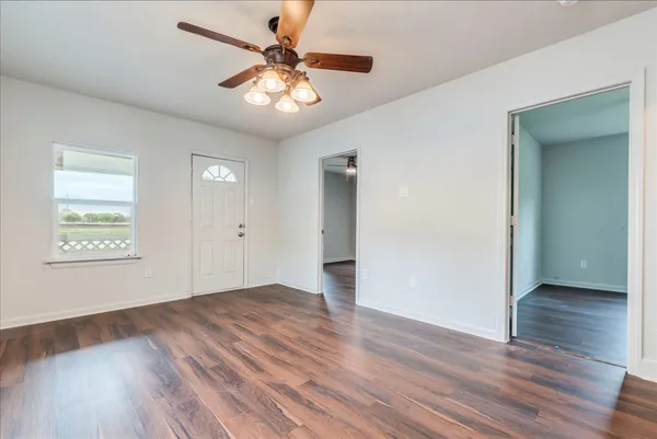 an empty room with wooden floor and windows
