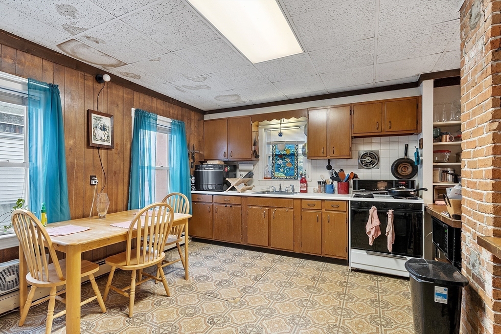 51 Crescent Street Wakefield, MA 01880 - Photo 9 of 20 a kitchen with stainless steel appliances granite countertop a stove a sink dishwasher a dining table and chairs with wooden floor
