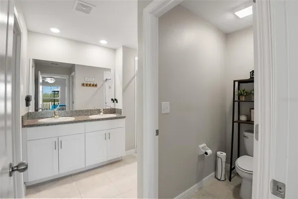 a bathroom with a granite countertop sink a toilet and a mirror