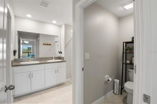 a bathroom with a granite countertop sink a toilet and a mirror