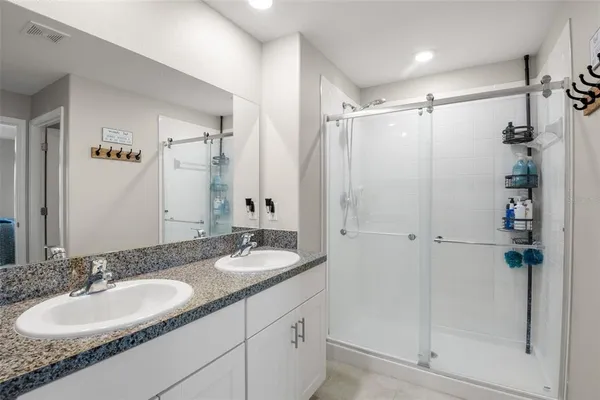 a bathroom with a double vanity sink mirror and shower