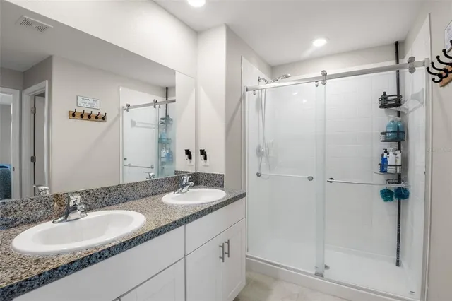 a bathroom with a double vanity sink mirror and shower