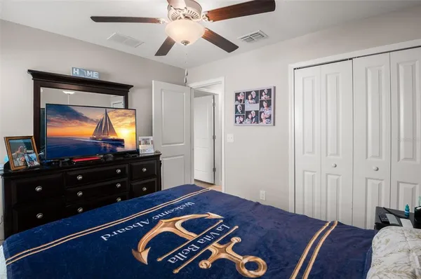 a bedroom with a bed and a flat tv screen on dresser