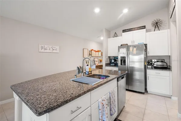 a kitchen with stainless steel appliances granite countertop a refrigerator a stove and a sink