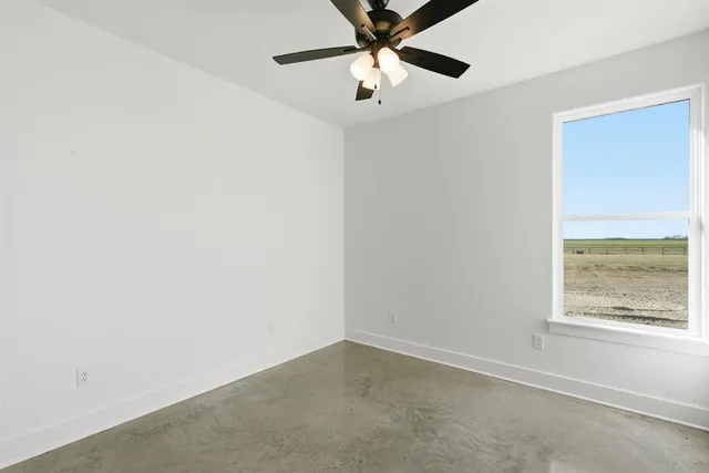 an empty room with a window and a fan