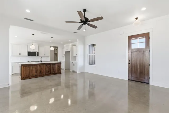 a living room with stainless steel appliances kitchen island granite countertop a refrigerator a sink a stove a dining table and chairs