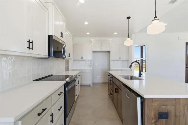 a kitchen with stainless steel appliances granite countertop a sink a stove and a refrigerator