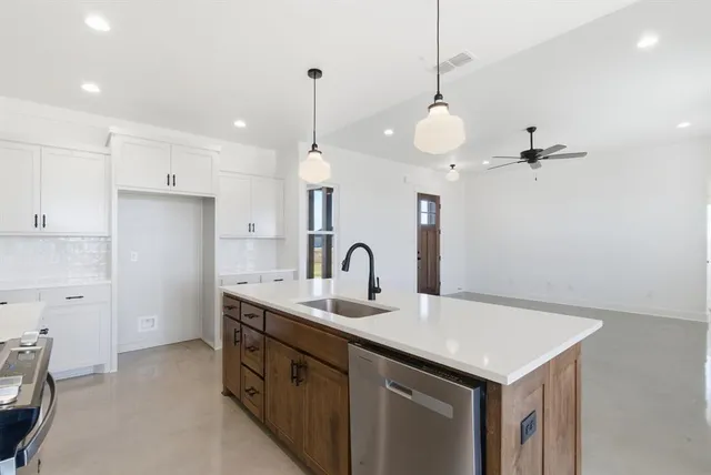 a kitchen with kitchen island a sink appliances and cabinets