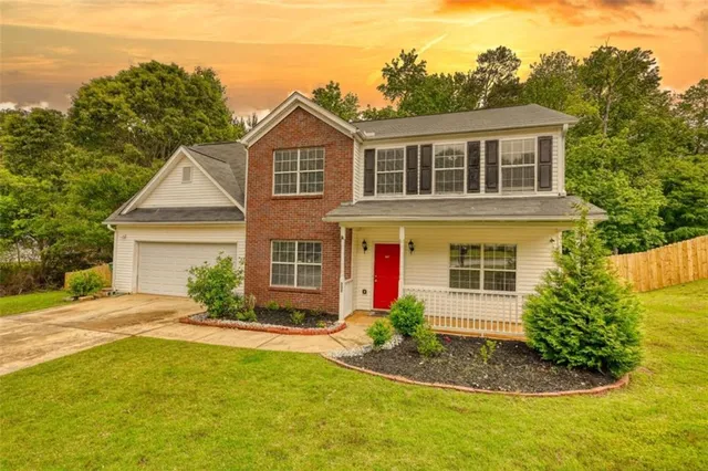 a front view of a house with a yard and trees