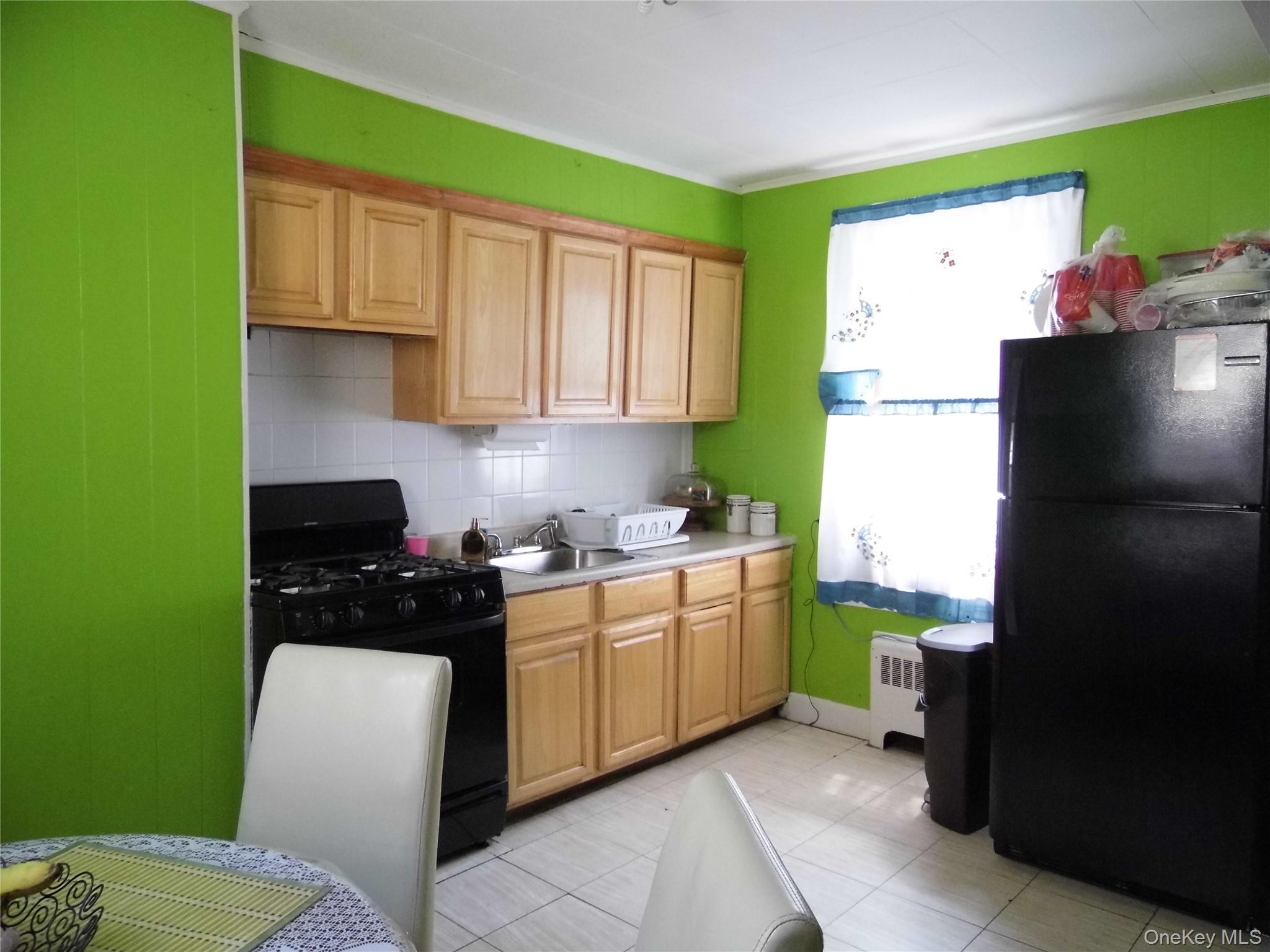86-75 80th Street Queens, NY 11421 - Photo 6 of 20 a kitchen with a sink a stove and a refrigerator