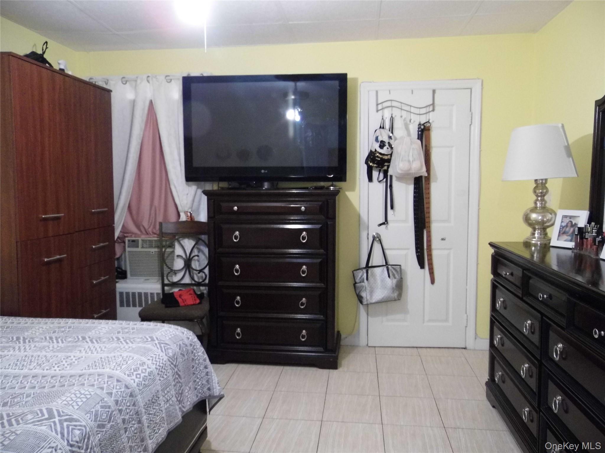 86-75 80th Street Queens, NY 11421 - Photo 10 of 20 a bedroom with a bed and a flat tv screen on dresser
