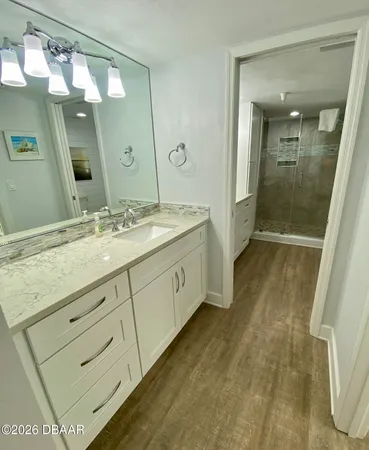 a bathroom with a granite countertop sink a toilet a mirror and shower
