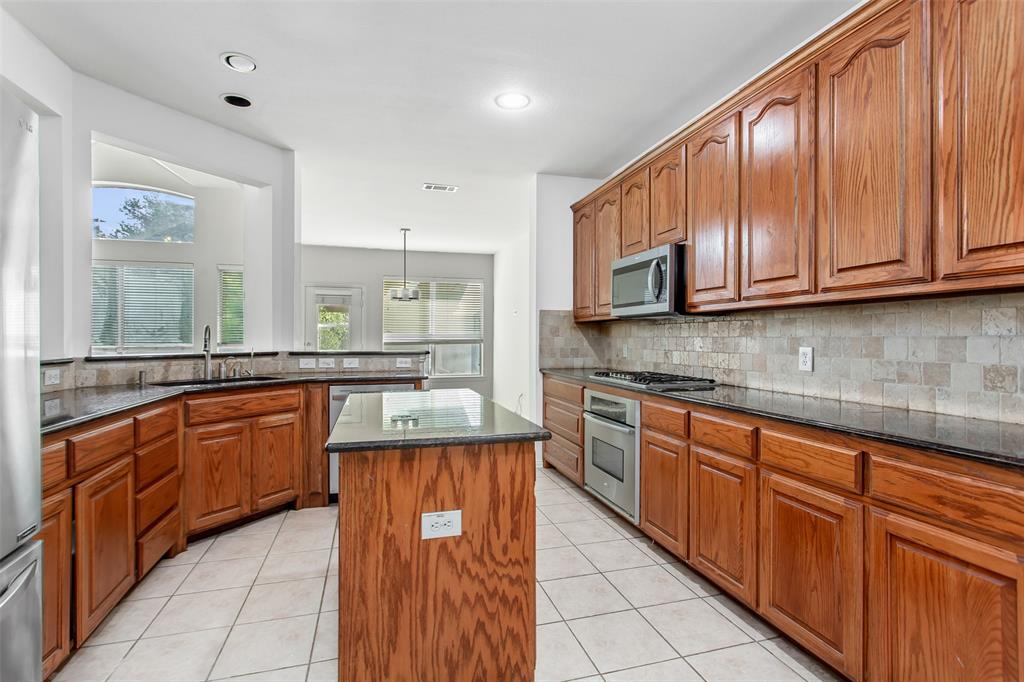 915 Falcon Trail Murphy, TX 75094 - Photo 11 of 40 a kitchen with stainless steel appliances granite countertop wooden cabinets a sink and dishwasher