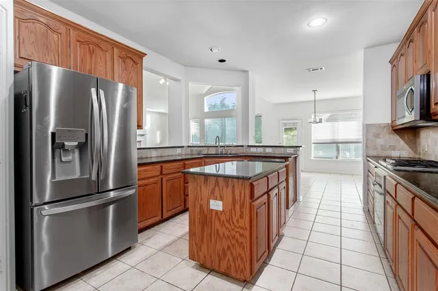 a kitchen with stainless steel appliances granite countertop a refrigerator a stove and a sink