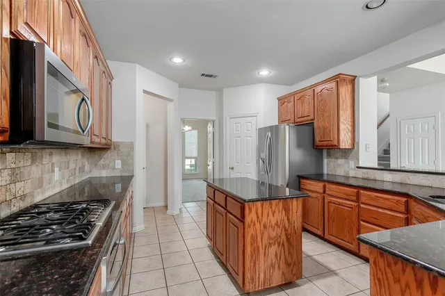 a kitchen with stainless steel appliances granite countertop a refrigerator and a stove top oven