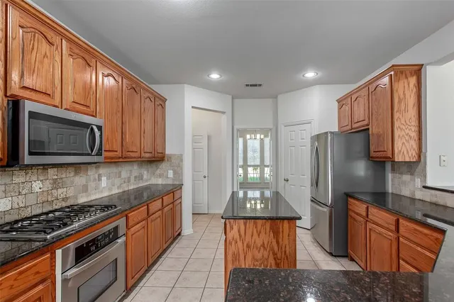 a kitchen with stainless steel appliances granite countertop a refrigerator a stove top oven a sink and dishwasher