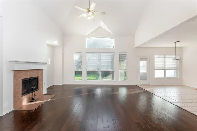 an empty room with wooden floor fireplace and windows