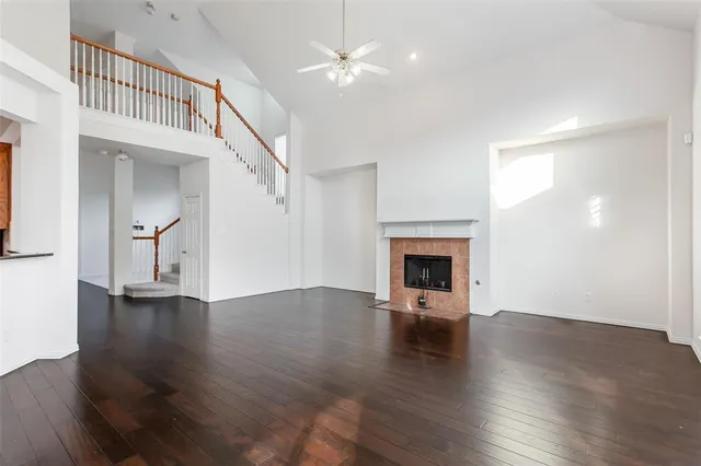 an empty room with wooden floor fireplace and windows