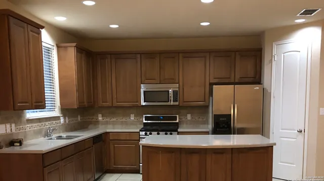 a kitchen with kitchen island a sink stainless steel appliances and cabinets