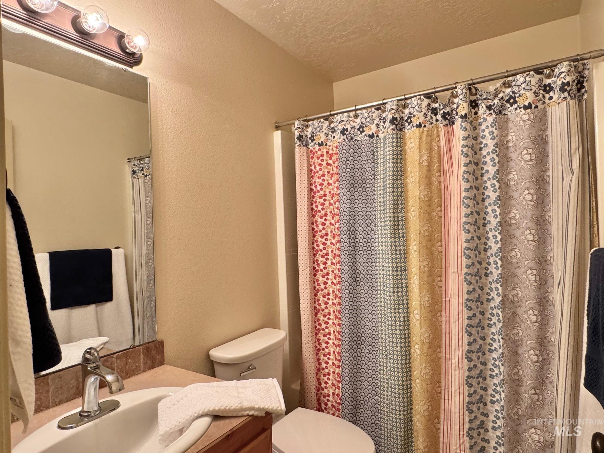 9299 Kemp Road Middleton, ID 83644 - Photo 31 of 50 Bathroom featuring a single vanity with a ceramic sink, a polished chrome faucet, and a wall-mounted mirror with an overhead light fixture
