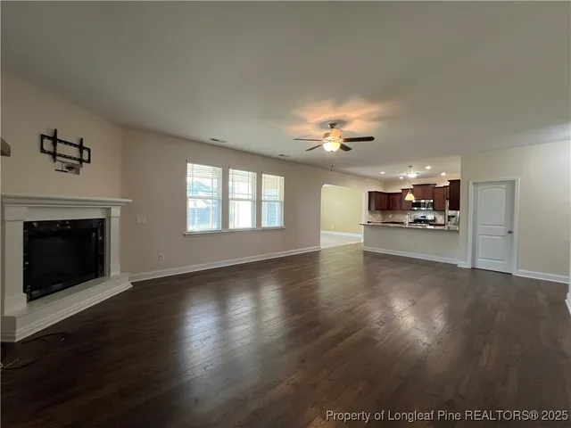 an empty room with wooden floor fireplace and chandelier fans