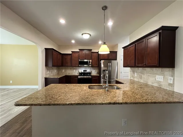 a kitchen with kitchen island granite countertop wooden cabinets and a sink