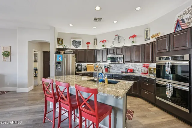 a kitchen with stainless steel appliances kitchen island granite countertop a dining table and chairs