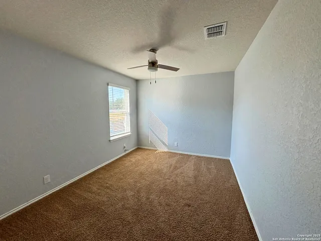 an empty room with windows and fan