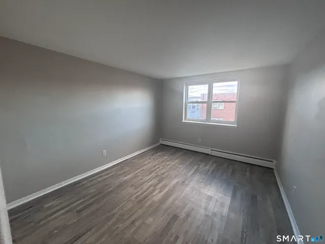a view of an empty room with wooden floor and closet