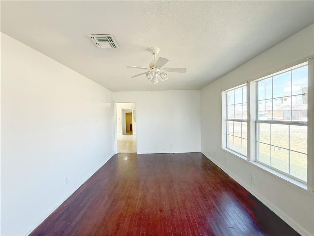 2325 1st Street Ingleside, TX 78362 - Photo 10 of 31 an empty room with wooden floor chandelier fan and windows