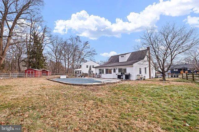 a view of white house with a big yard and large trees