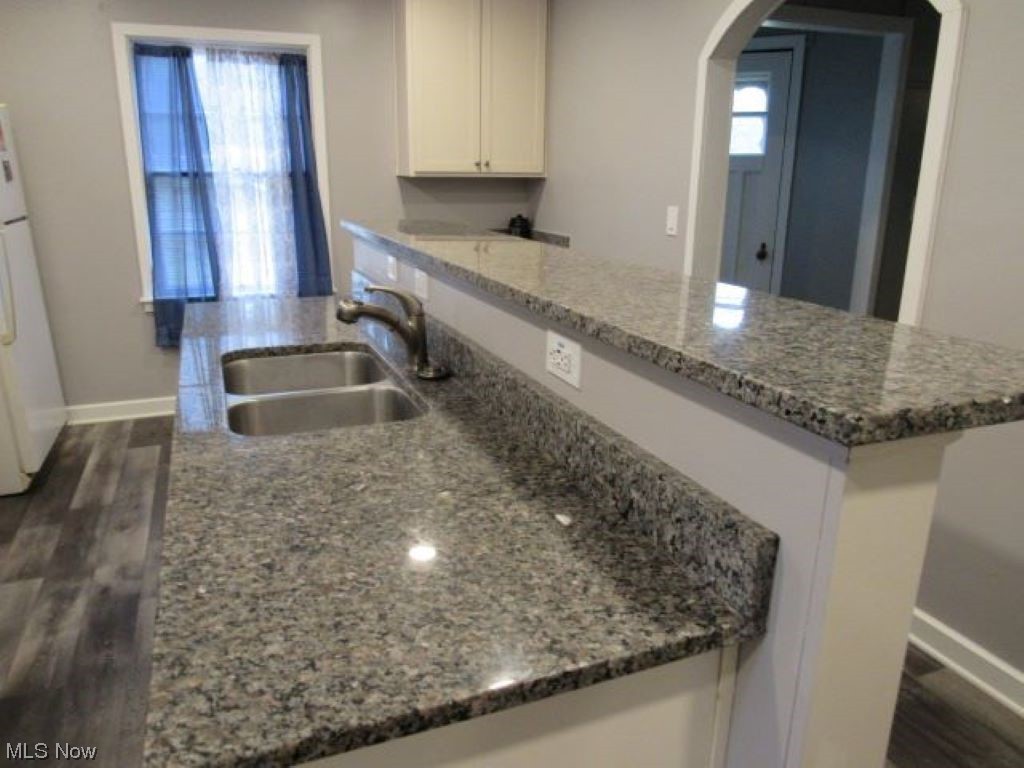 8528 Lafayette Road Lodi, OH 44254 - Photo 7 of 22 Kitchen featuring breakfast bar, sink, white cabinetry, stone counters, and dark wood-type flooring