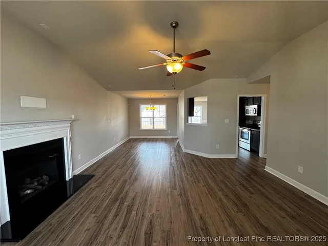 a view of a livingroom with a hardwood floor a ceiling fan and a window